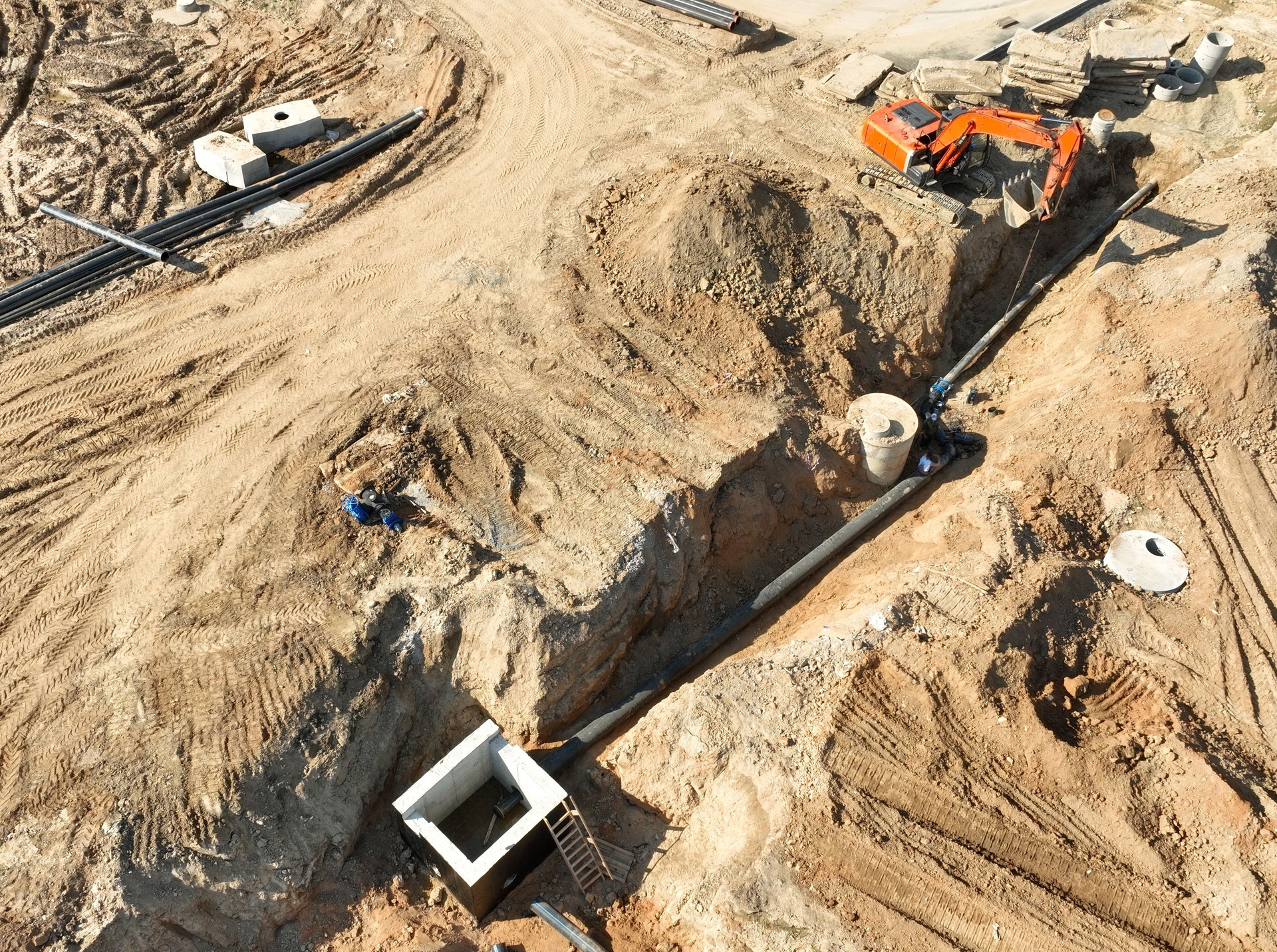 Sewage drainage system mounting at construction site. Excavator during laying sewer pipe and main systems.