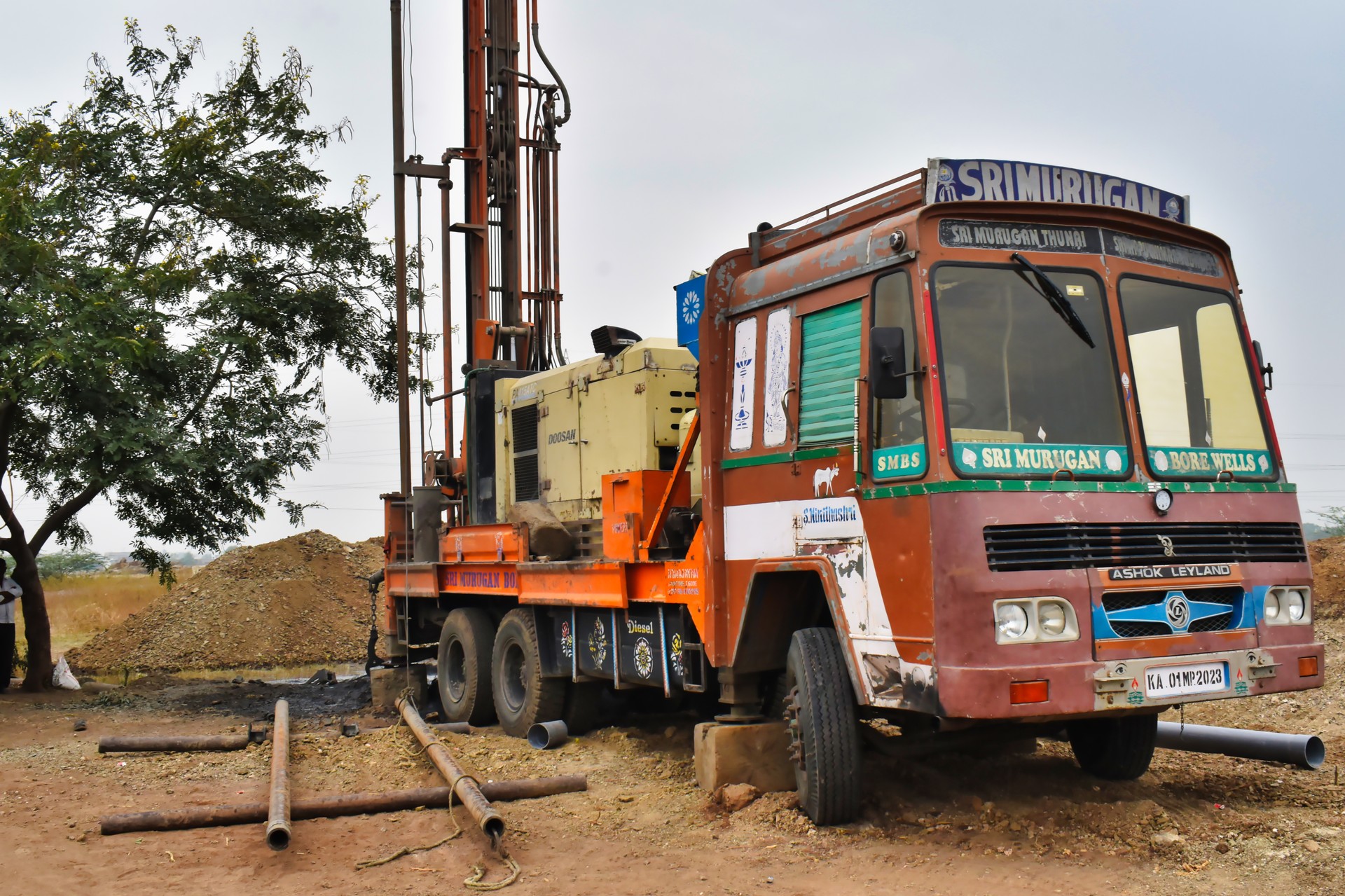 Labours are unloading the casing pipe with a rope into the borewell hole after compiling the borewell by bore well drilling truck.